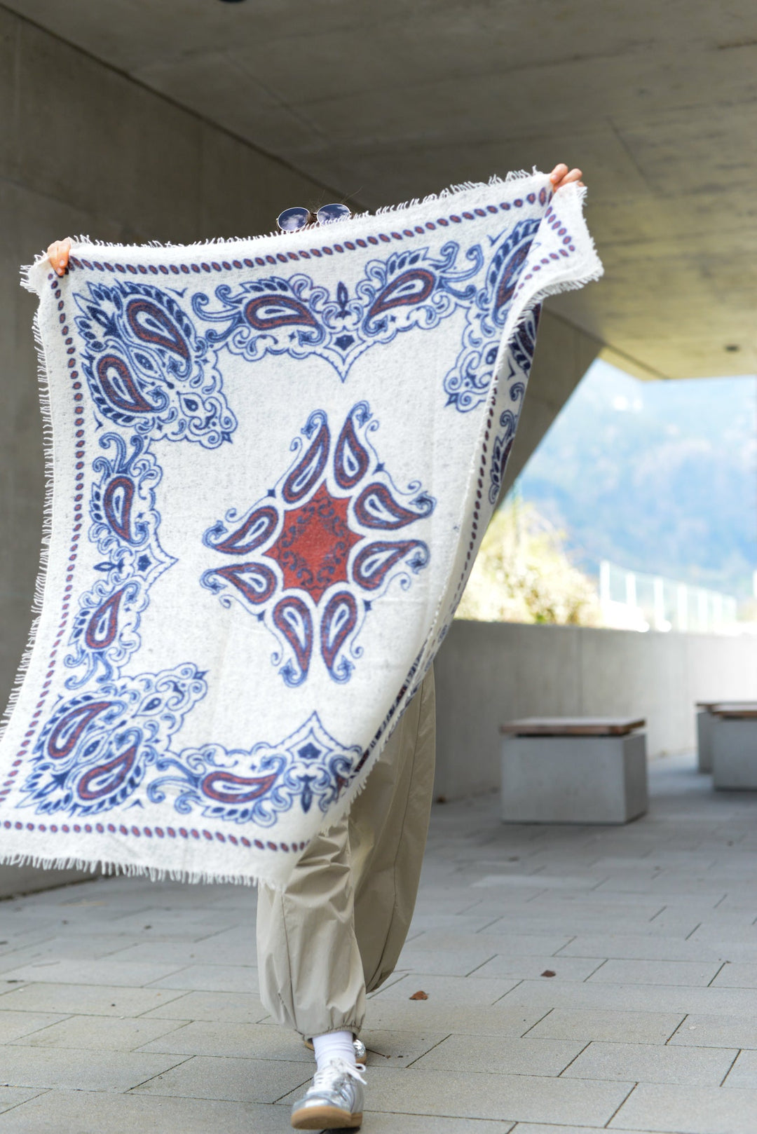 KaschmirTuch mit Paisley-Muster in 100 x 100 cm, Model hält das Bandana, damit die Größe und das Druckmotiv gut erkennbar ist
