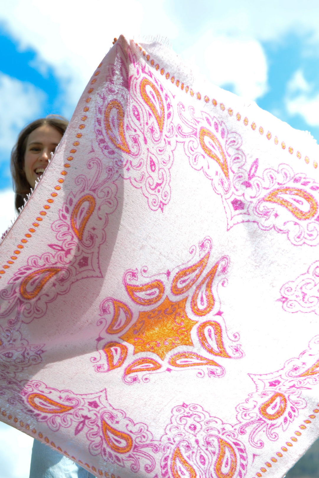 Model hält das große Kaschmir Bandana Paisley aus Light Cashmere in Rosa vor dem Körper
