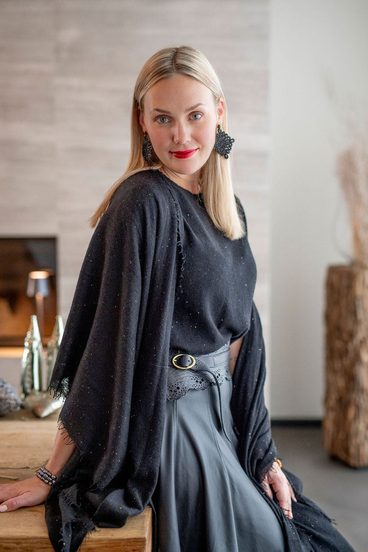 Eleganter Kaschmirschal für Damen aus reinem Kaschmir mit feinen, eingearbeiteten Pailletten und mit dezenten Fransen in der Farbe Schwarz, Model trägt Shal über den Schultern
