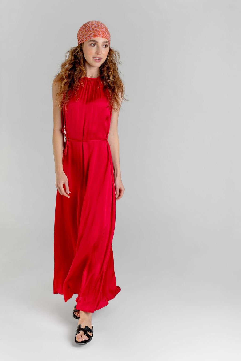 Model trägt knöchellanges Off‑Shoulder Kleid Gloria in Rot, gestylt mit Sandalen und einem Kaschmir-Kopftuch