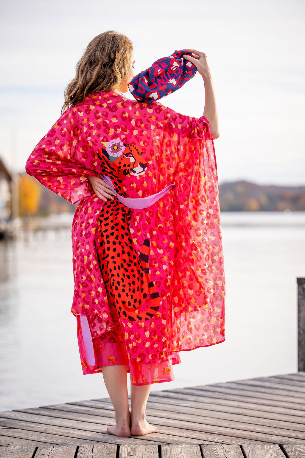 

Model trägt Baumwollkimono Catalina‑cs in Pink am See, Rückansicht mit Leopraden-Print


