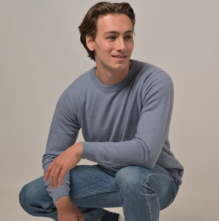 Model trägt Klassischen Herren-Kaschmirpullover mit Rundhalsausschnitt in Denim aus 100 % Kaschmir zur Jeans