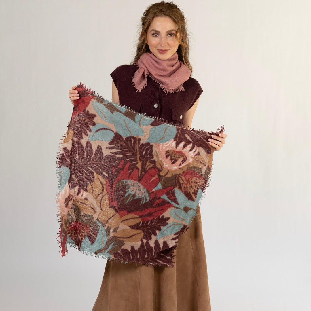Kaschmir Bandana mit Blumenmotiv 65 x 65 cm mit Fransen aus 100% Light Cashmere gehalten von einem Model, damit die quadtratische Größe und das Blumenmuster gut zu erkennen ist