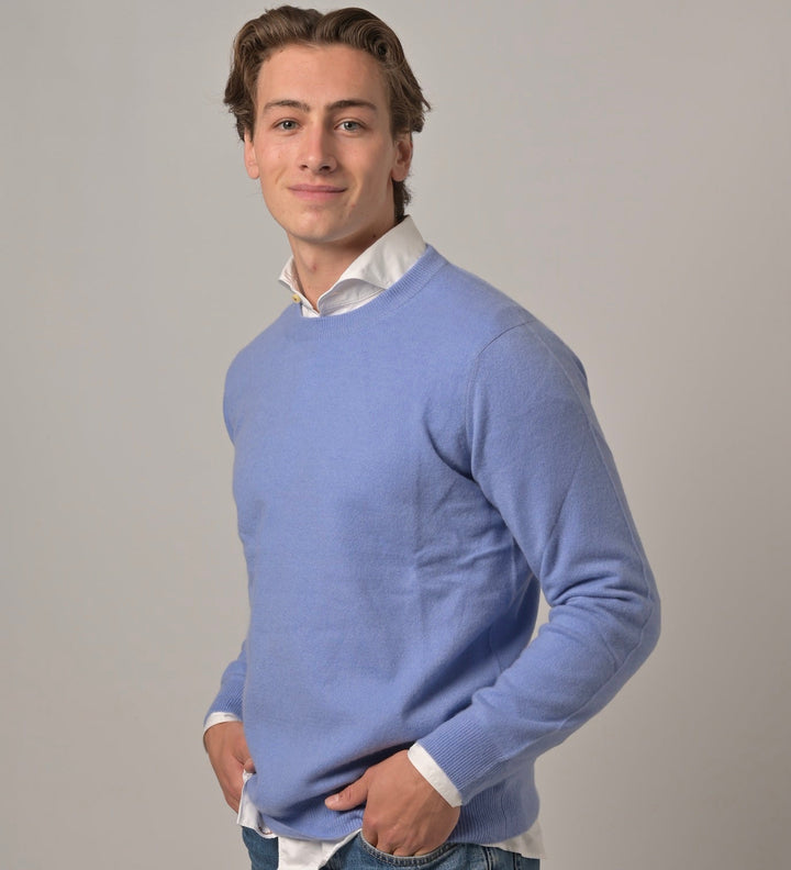 Model trägt klassischen Herren-Kaschmirpullover mit Rundhalsausschnitt in Arctic Blau aus 100 % Kaschmir über einem Herrenhemd