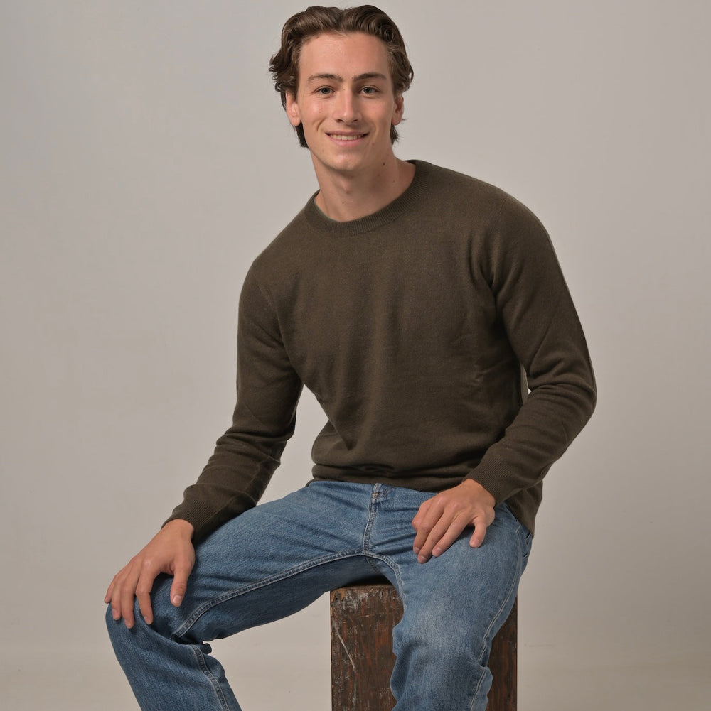 Model trägt klassischen Herren-Kaschmirpullover mit Rundhalsausschnitt in der Farbe Alligator aus 100 % Kaschmir zur Jeans