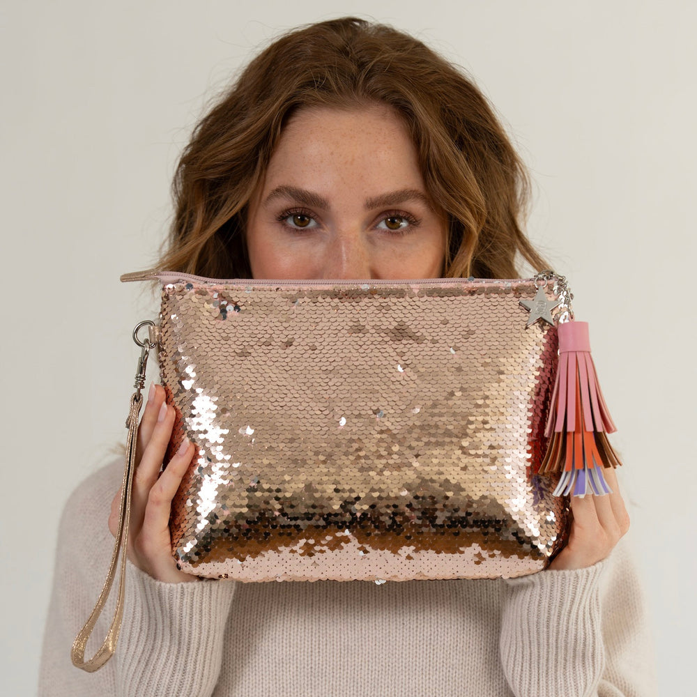 Model hält kleine Clutch mit Pailletten und PompPom-Anhänger in Gold von cute stuff