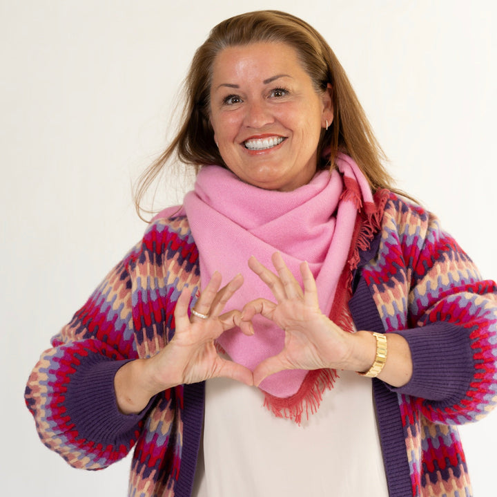 Corinna trägt das gestrickte Kaschmirtuch Mila-cs in Pink von cute stuff als Halstuch und kombiniert es mit der Strickjacke Liv
