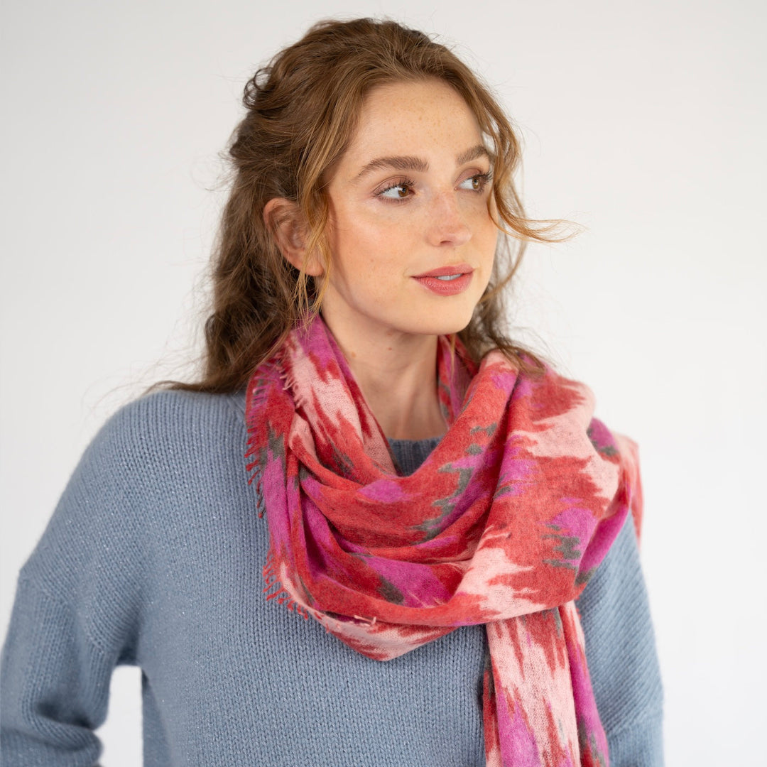 Tragebild: Kaschmir-Schal „Ikat Flow“ in Chilli aus 100 % Kaschmir mit abstraktem Ikat-Muster in Rot, Pink und Grau sowie feinem Fransensaum von cute stuff
