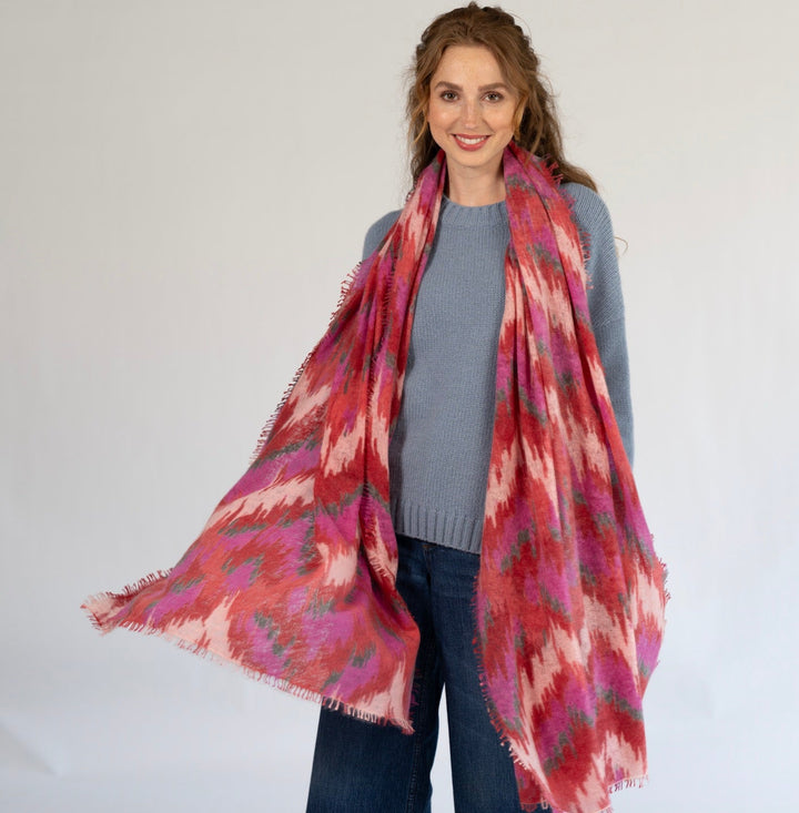 Tragebild: Kaschmir-Schal „Ikat Flow“ in Chilli aus 100 % Kaschmir mit abstraktem Ikat-Muster in Rot, Pink und Grau sowie feinem Fransensaum von cute stuff